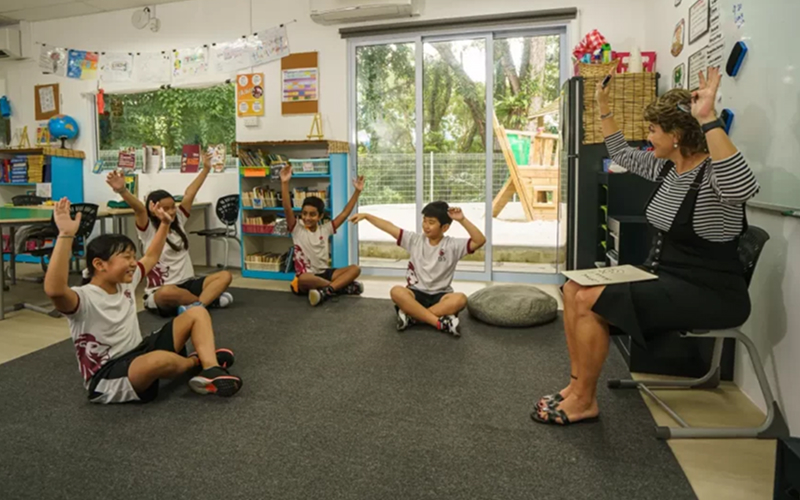 Teacher engaging with students in a small EAL classroom setting.