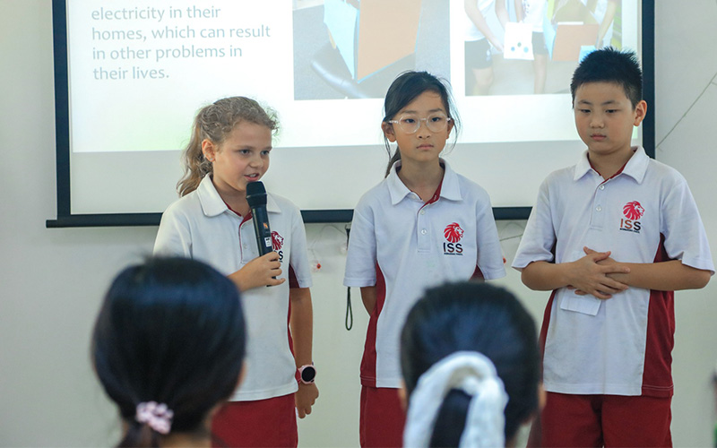 Elementary students giving a presentation with a microphone.