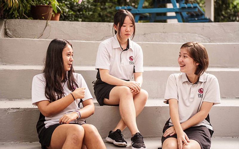 High school students chatting on campus steps.
